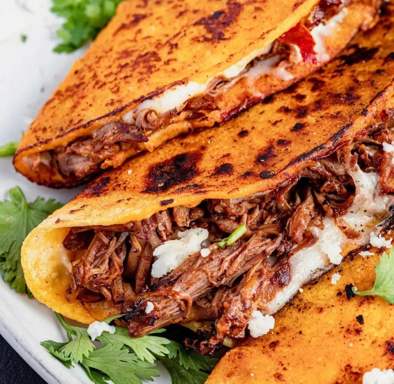 Cheesy quesabirria tacos crisped on the griddle